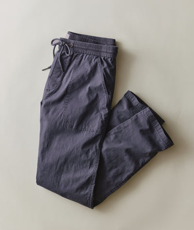 A pair of dark slate blue drawstring pants laid flat on a light beige background.